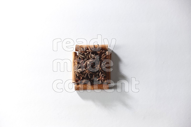 A single square of cinnamon sticks full of star anise on white flooring