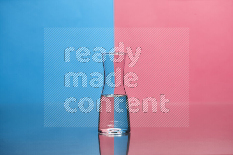 The image features a clear glassware filled with water, set against blue and pink background