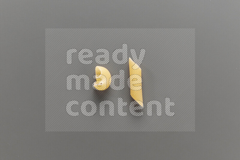 Pipe pasta with other types of pasta on grey background