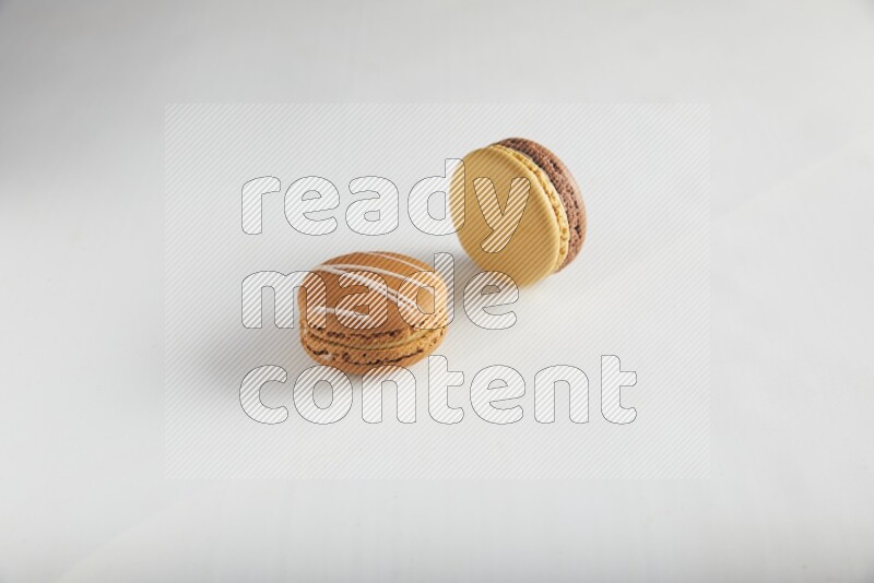 45º Shot of of two assorted Brown Irish Cream, and Yellow, and Brown Chai Latte macarons on white background