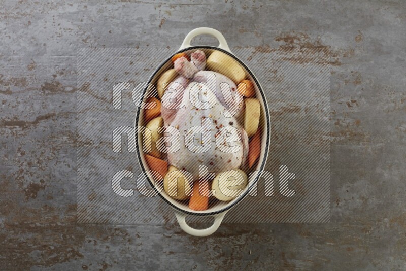 whole raw chicken on in a white ceramic pot direct on a rustic grey background