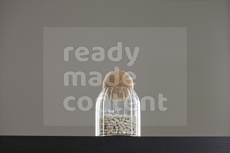 White beans in a glass jar on black background