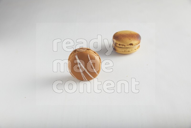 45º Shot of of two assorted Brown Irish Cream, and Yellow Crème Brulée macarons on white background