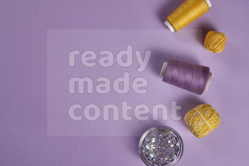 A yellow and purple collection of sewing and tailoring tools arranged on a purple background