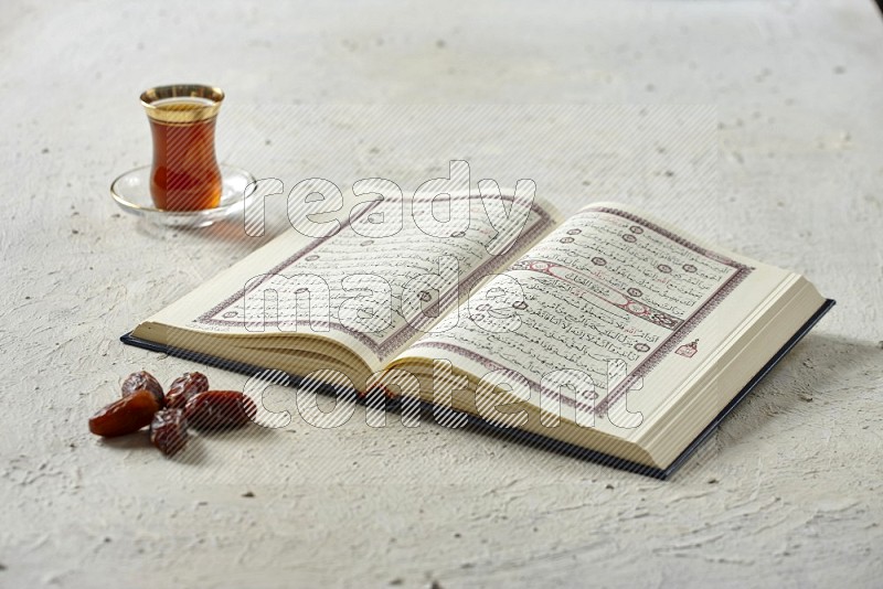 Quran with dates, prayer beads and different drinks on textured white background