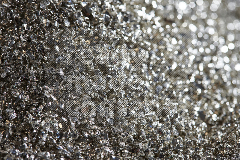 Silver shimmering fragments of glass scattered on a black background