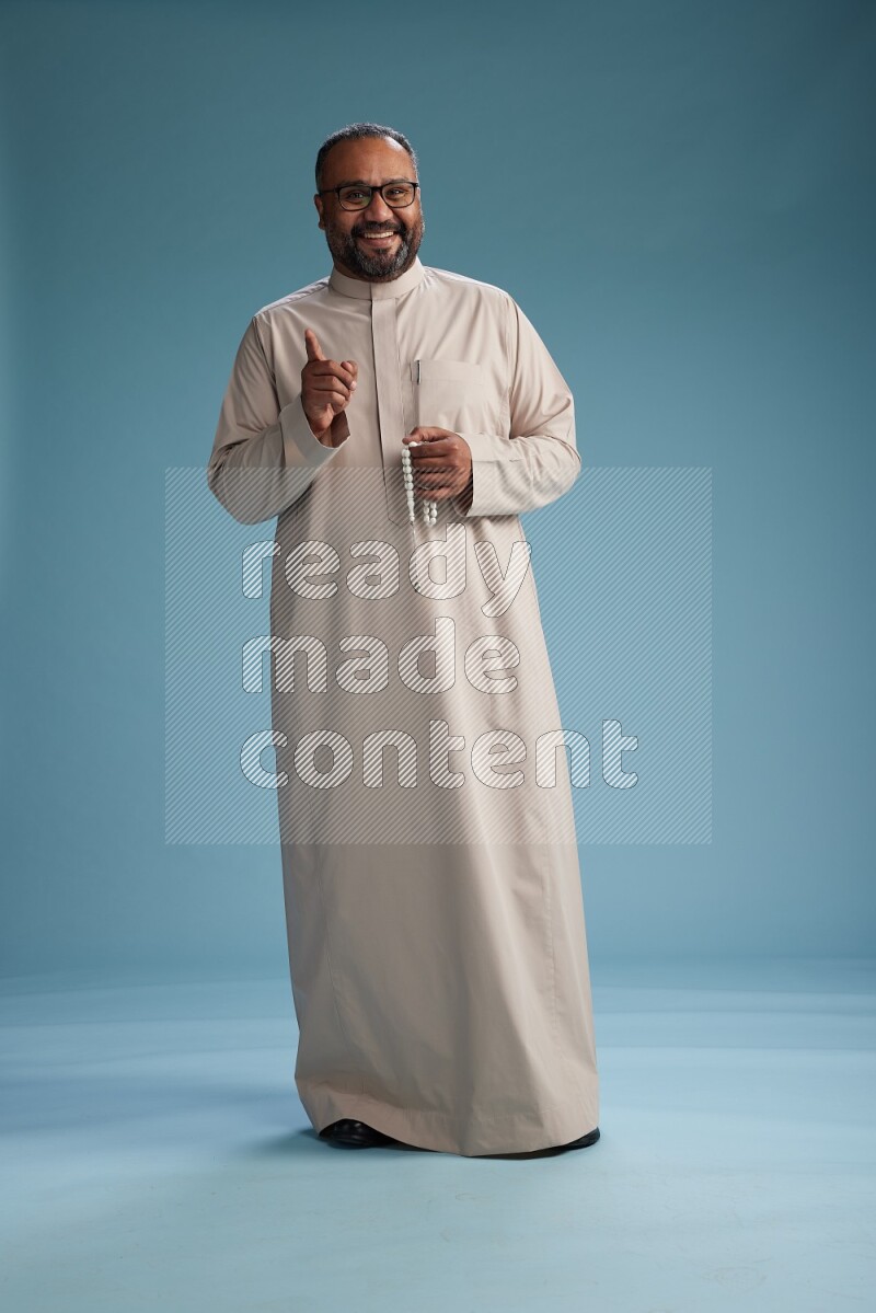 Saudi Man without shimag Standing Interacting with the camera on blue background