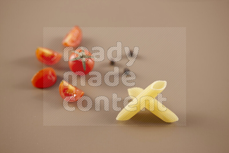 Raw pasta with different ingredients such as cherry tomatoes, garlic, onions, red chilis, black pepper, white pepper, bay laurel leaves, rosemary and cardamom on beige background