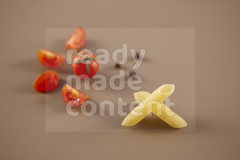 Raw pasta with different ingredients such as cherry tomatoes, garlic, onions, red chilis, black pepper, white pepper, bay laurel leaves, rosemary and cardamom on beige background