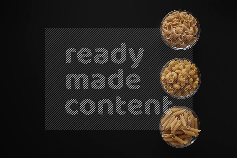 Different pasta types in 3 glass bowls on black background