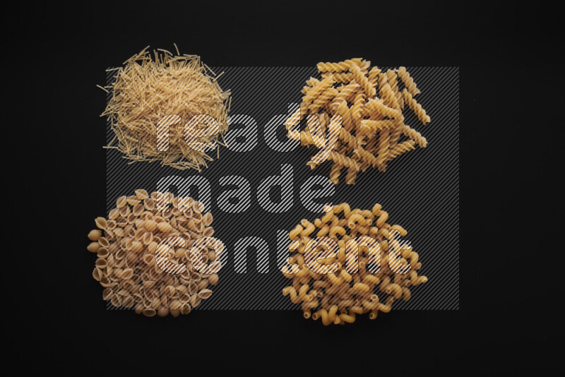 Different pasta types in bunches on black background