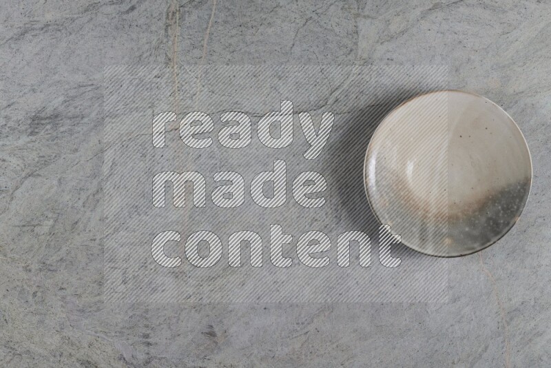 A multicolored pottery plate on grey marble background