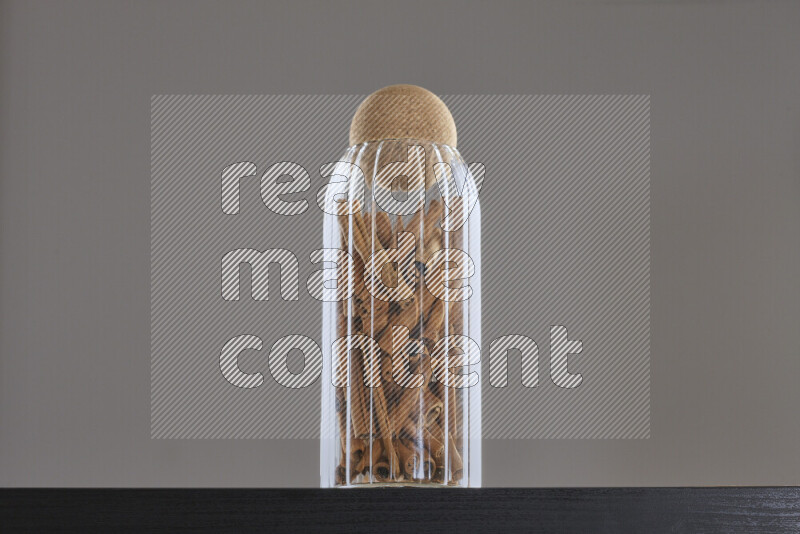 Cinnamon sticks in a glass jar on black background