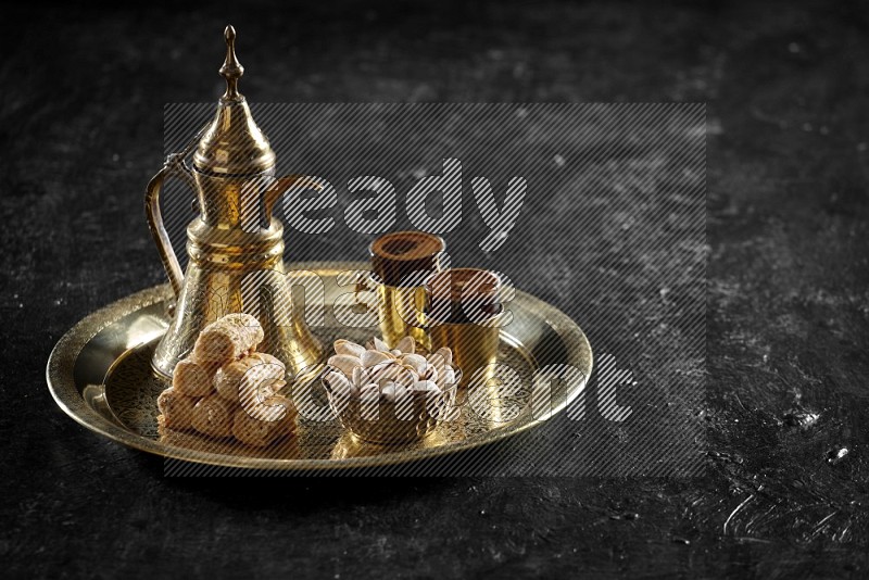 Oriental sweets with nuts and a drink on a metal tray in a dark setup