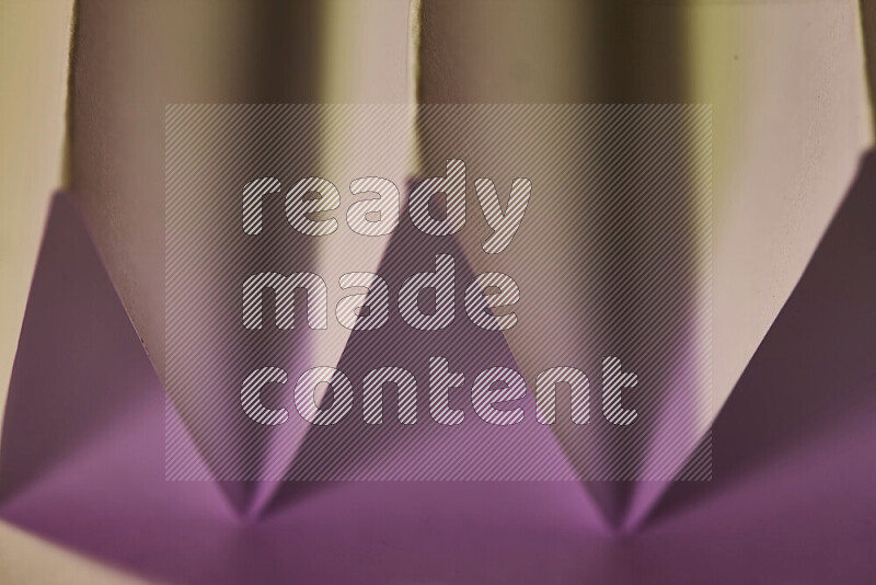 A close-up abstract image showing sharp geometric paper folds in pink gradients and warm tones