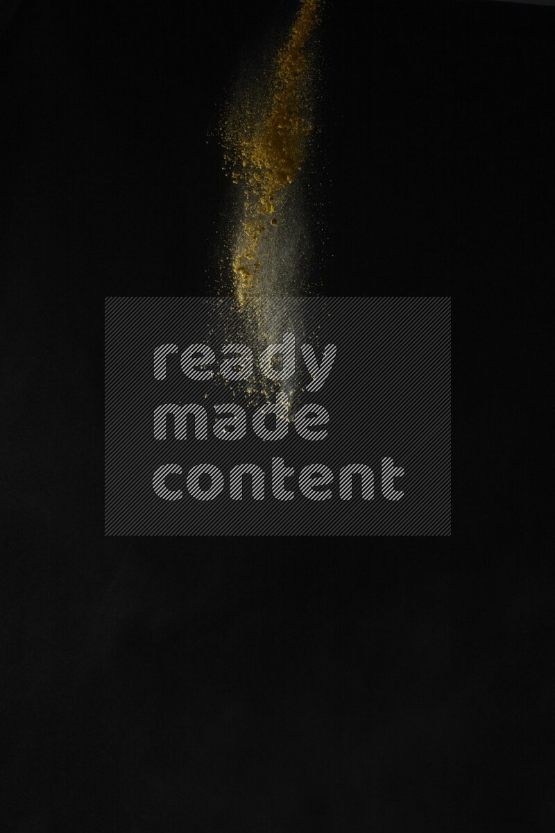 A side view of yellow powder explosion on black background