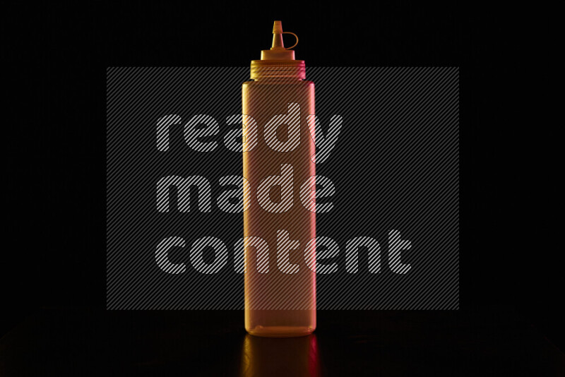 A squeeze bottle with colored rim light against black background