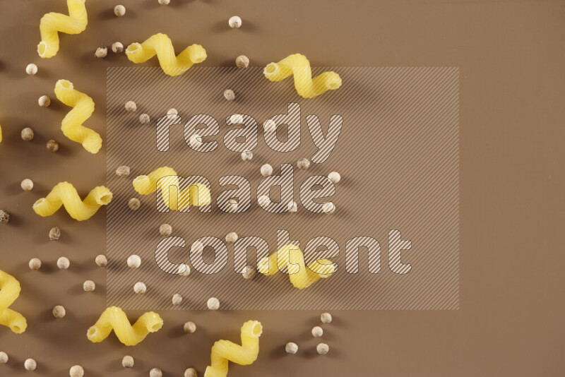 معكرونة مع مكونات متنوعة من الطماطم والثوم والبصل والفلفل الأحمر والفلفل الأسود والفلفل الأبيض وأوراق الغار وإكليل الجبل والهيل على خلفية بيج