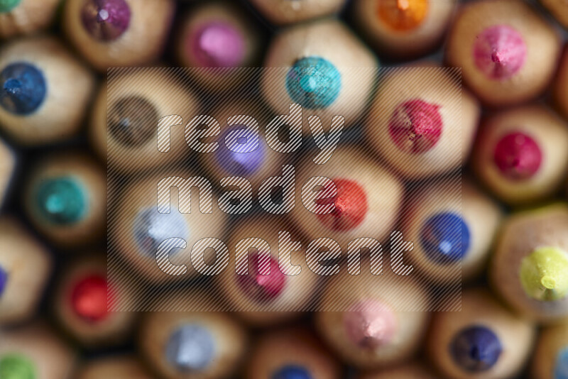 تظهر الصورة لقطة علوية لأقلام تلوين خشبية علي خلفية رمادية