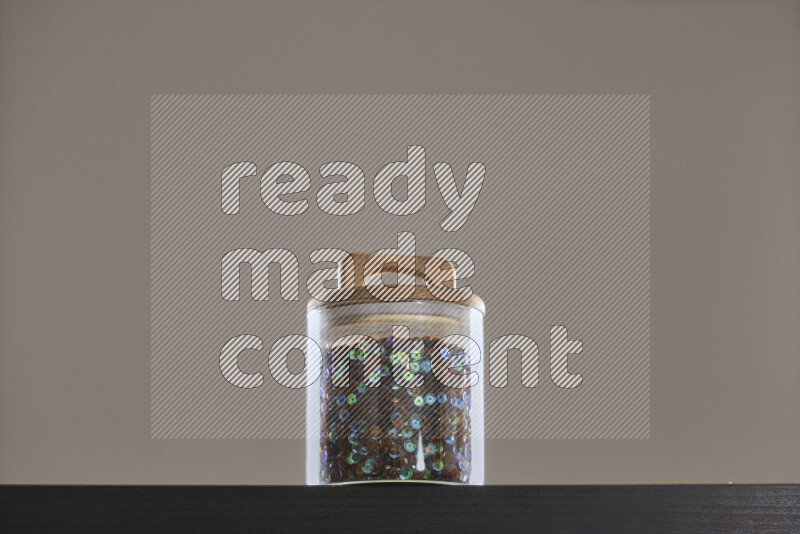 Sequins in a glass jar on black background