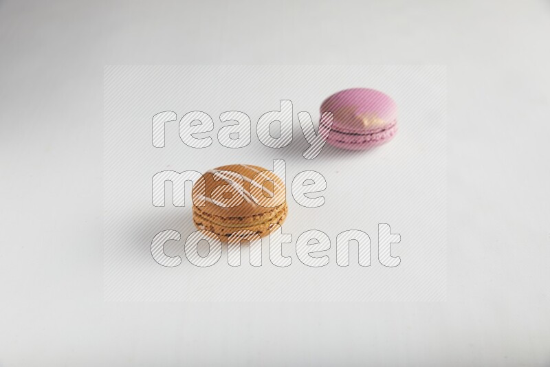 45º Shot of of two assorted Brown Irish Cream, and Purple Strawberry macarons on white background