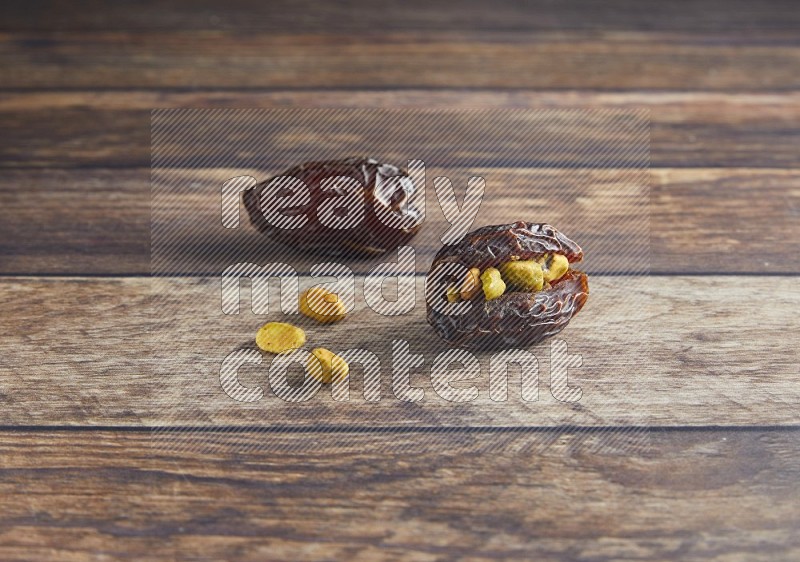 two pistachio stuffed madjoul date on a wooden background