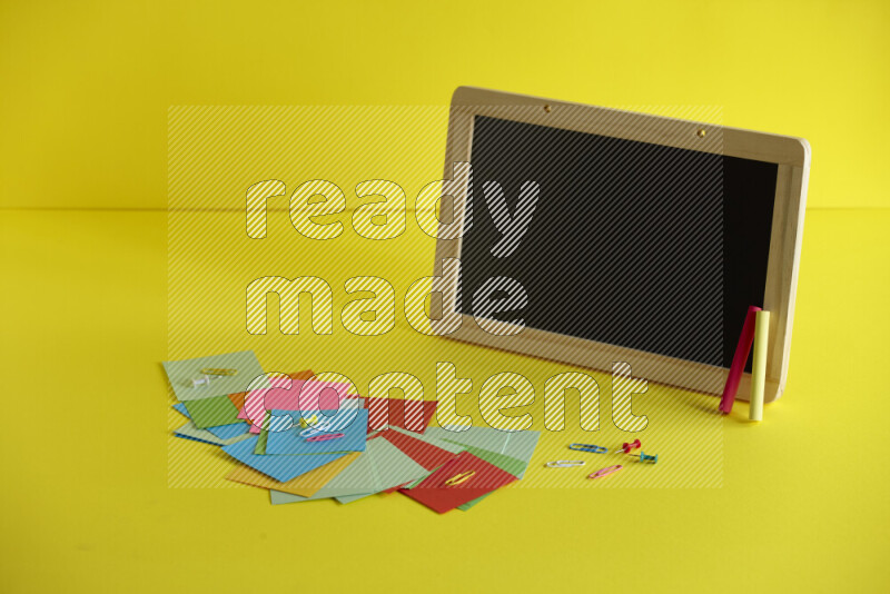 A blackboard with different school supplies on yellow background