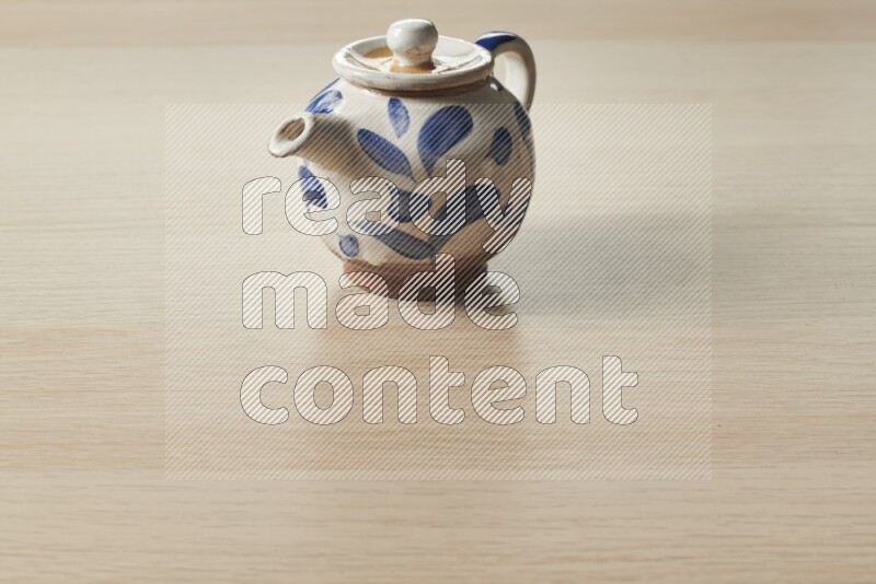 A pottery teapot on light wooden background