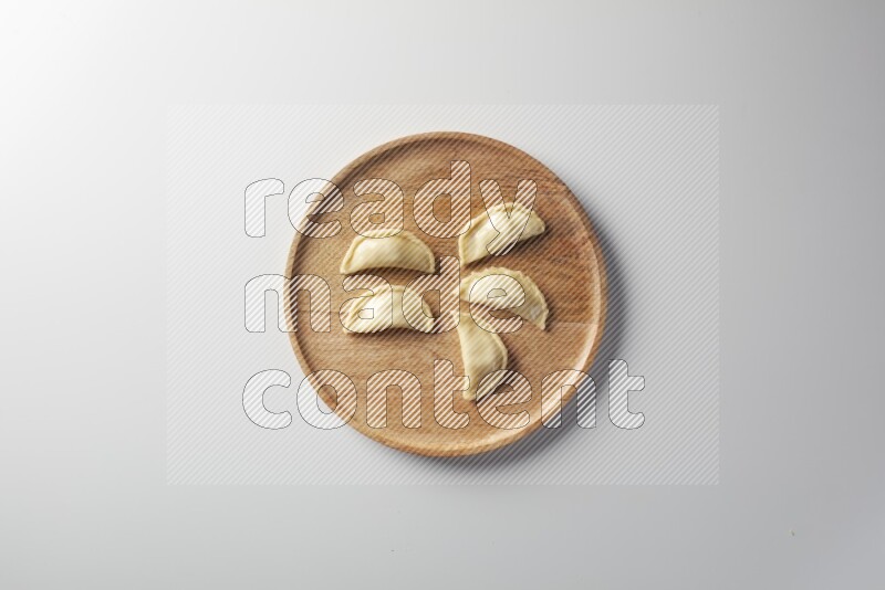Five Sambosas on a wooden round plate on a white background