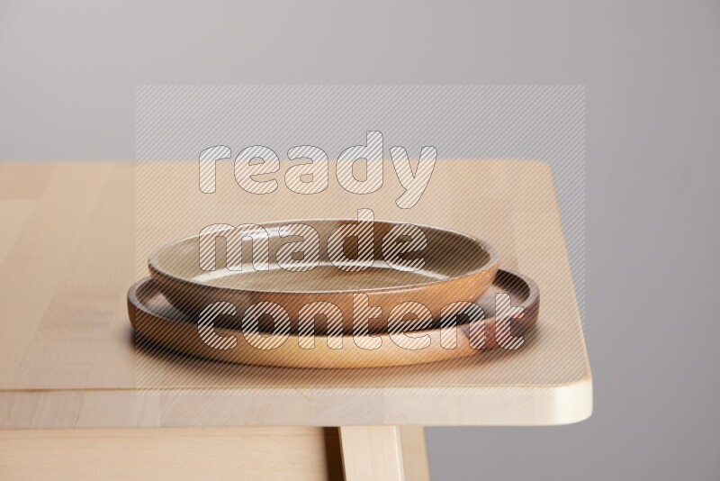 multi-colored pottery Plate placed on a light colored wooden tray on the edge of wooden table