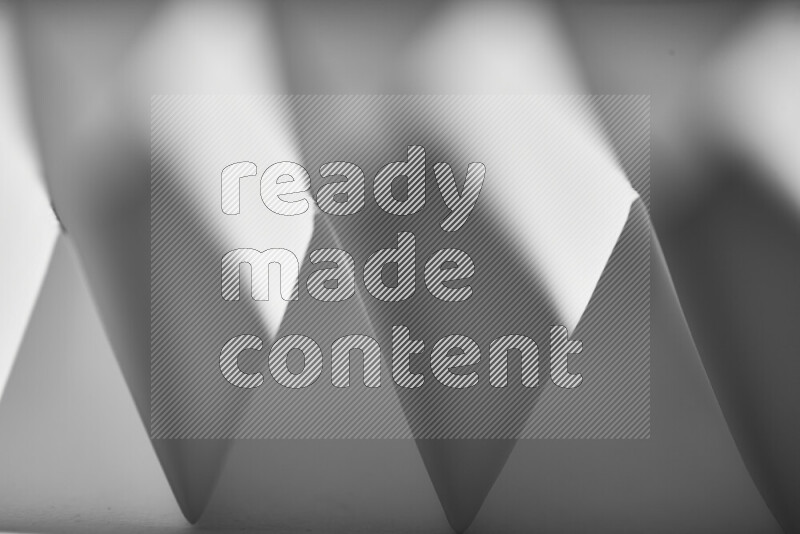 صورة مجردة مقربة تظهر طيات ورقية هندسية حادة بتدرجات اللون الرمادي