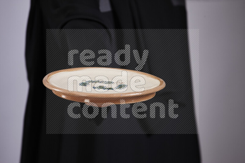 A woman in black abaya holding different pottery essentials in different positions