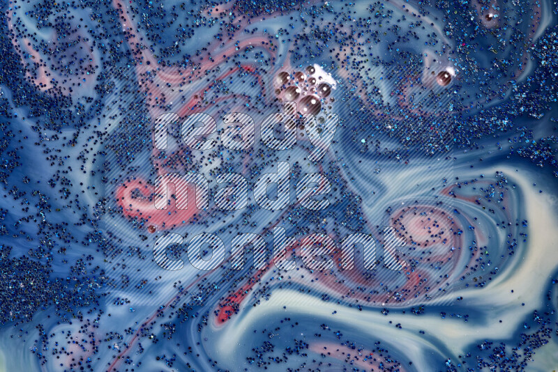A close-up of sparkling blue glitter scattered on swirling blue and red background