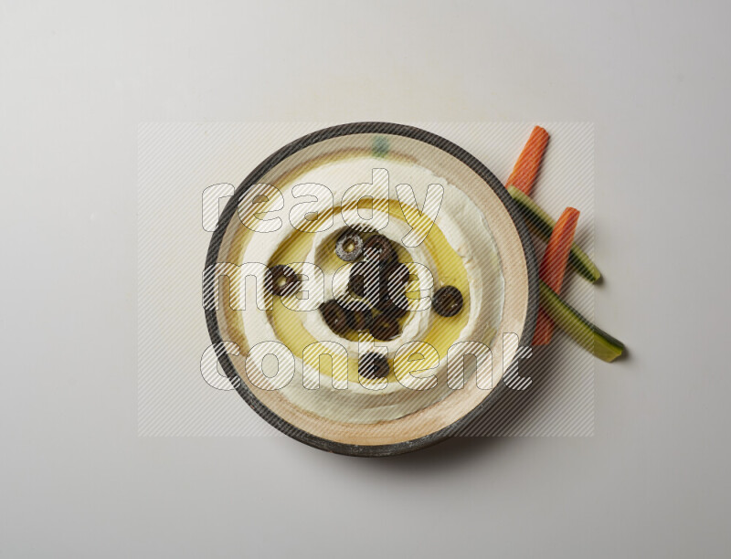 Lebnah garnished with sliced olives in a pottery plate on a white background