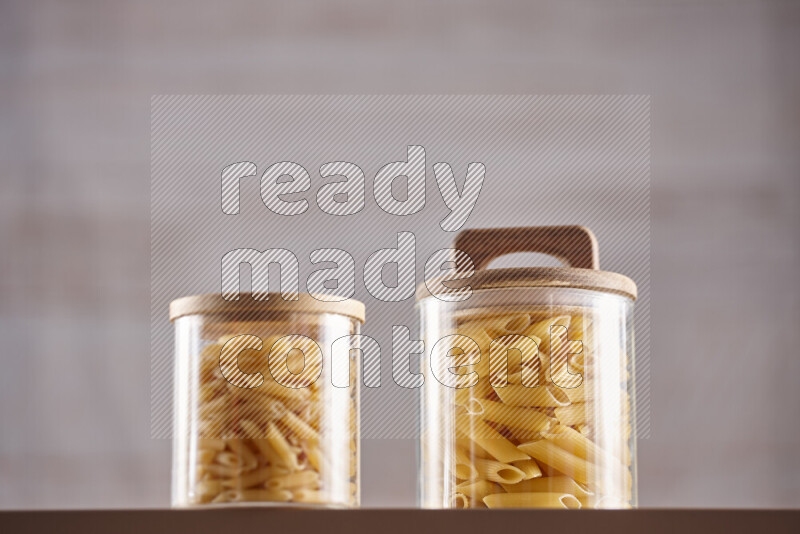 Raw pasta in glass jars on beige background