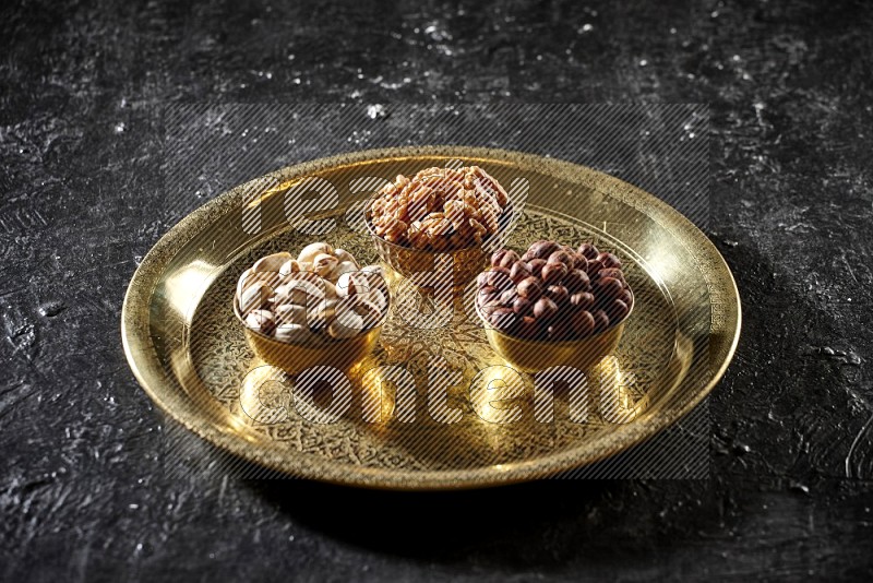 Nuts in metal bowls on a tray in a dark setup