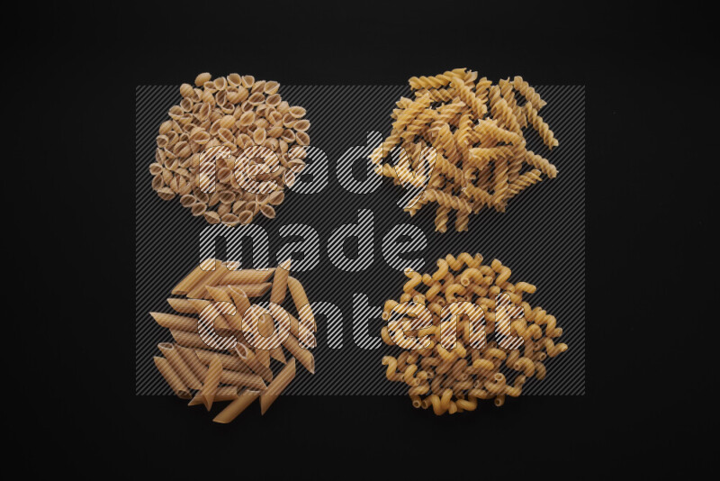 Different pasta types in bunches on black background