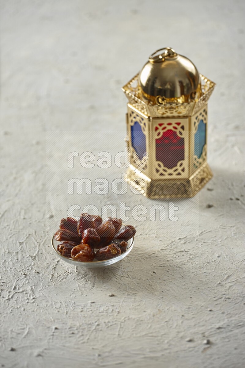 A golden lantern with different drinks, dates, nuts, prayer beads and quran on textured white background