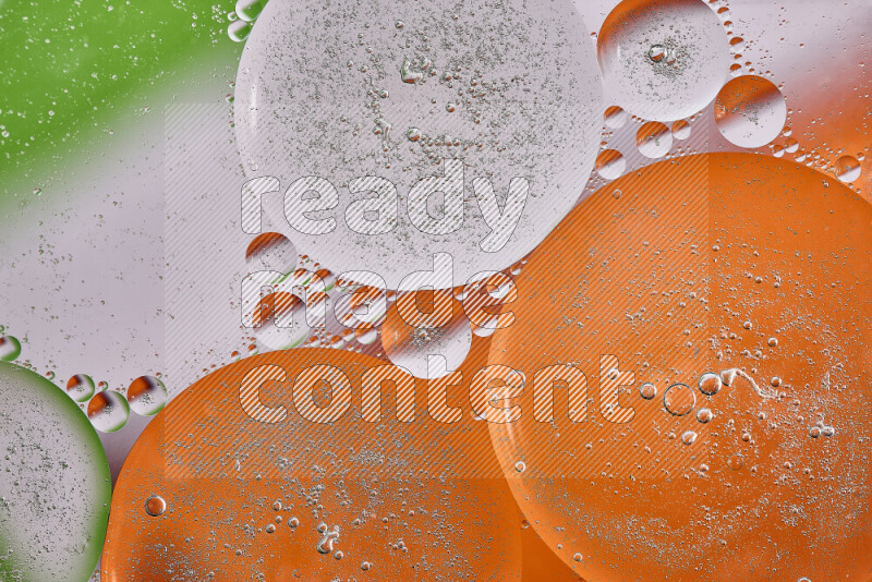 Close-ups of abstract oil bubbles on water surface in shades of orange, green and white