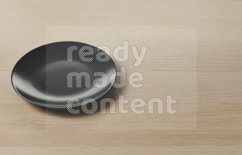 A black ceramic circular plate on light wooden background