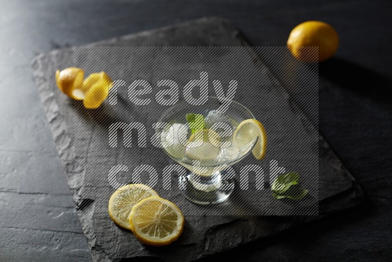 A glass of lemon juice with a lemon slice on black background