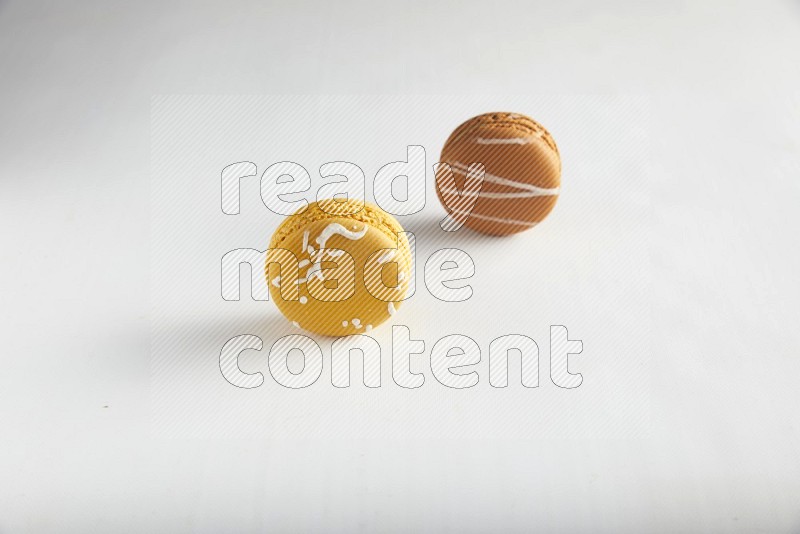 45º Shot of of two assorted Brown Irish Cream, and Yellow Piña Colada macarons on white background