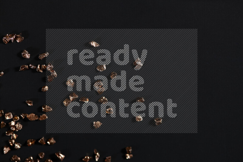 قطع زجاجية برونزية لامعة متناثرة على خلفية سوداء