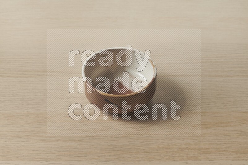 وعاء فخاري متعدد الألوان على خلفية خشبية فاتحة