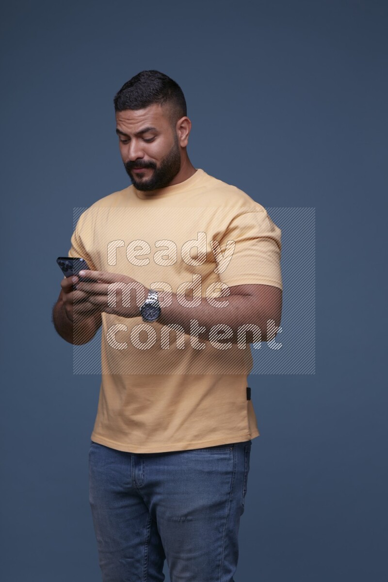 A man Texting on his phone on Blue Background wearing Orange T-shirt