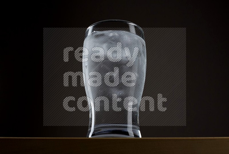 Low angle shot of a glass of water and ice on grey background