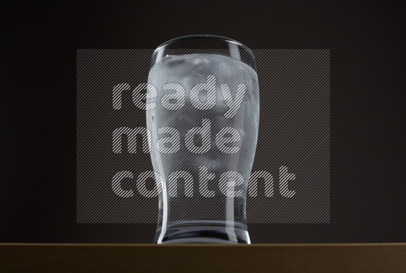Low angle shot of a glass of water and ice on grey background