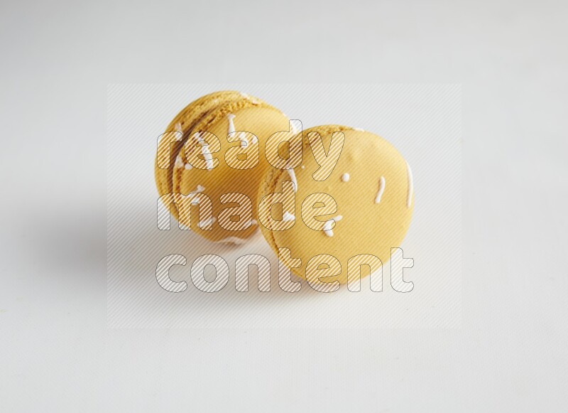 45º Shot of two Yellow Piña Colada macarons on white background