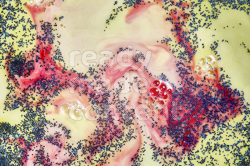 A close-up of sparkling blue glitter scattered on swirling yellow and red background