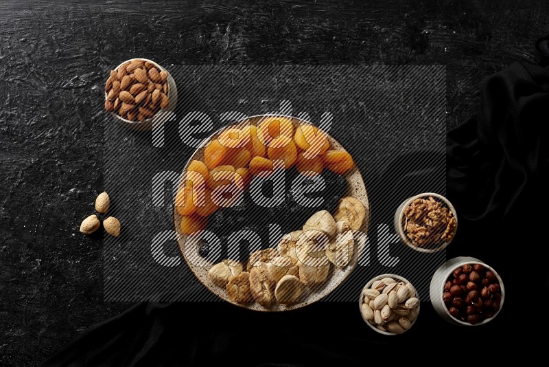 Dried fruits in a pottery bowl with nuts in a dark setup